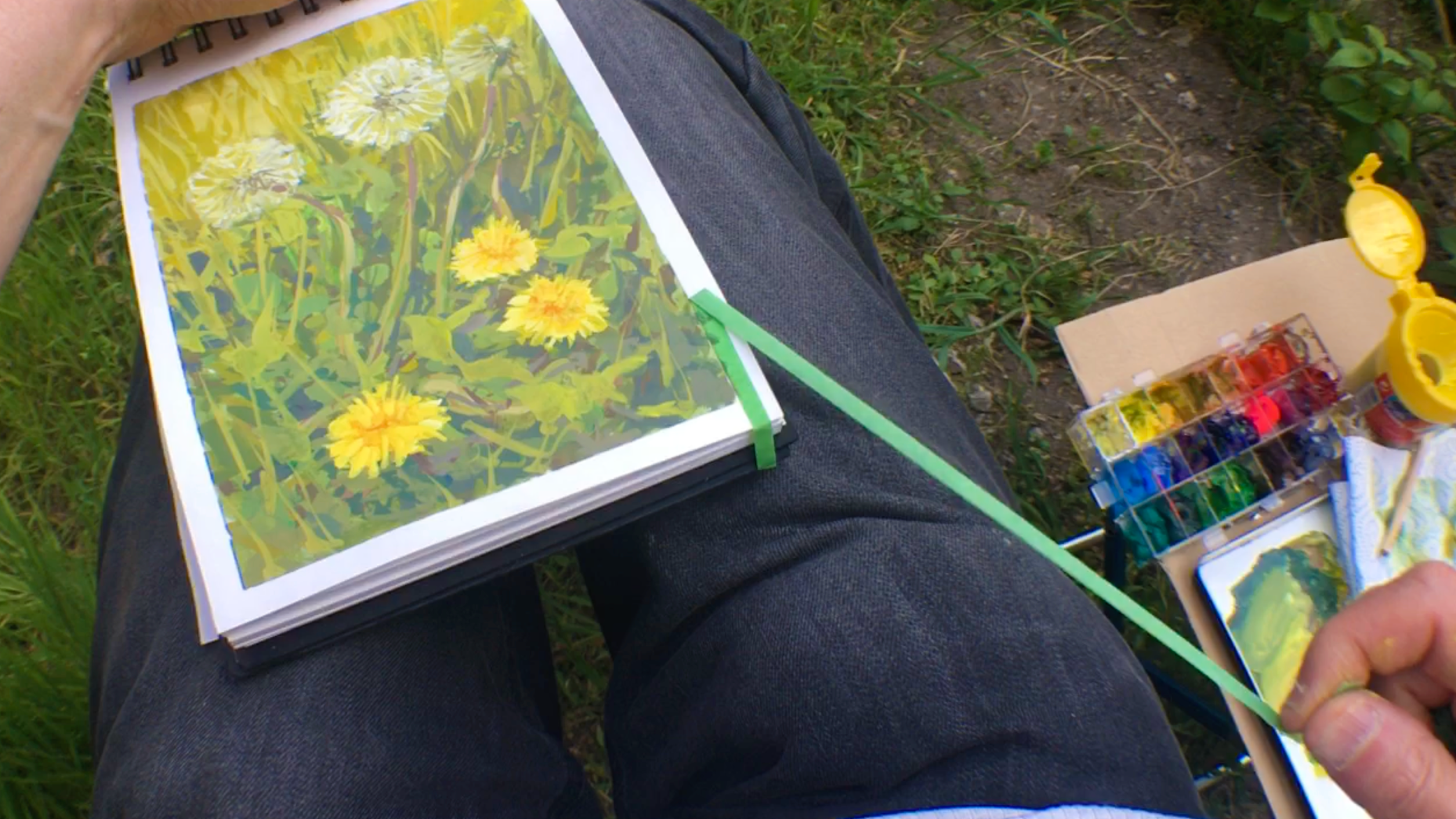 Retrait de l’adhésif après une gouache peinte en plein air Artiste retirant le ruban adhésif autour d’une gouache de pissenlits peinte en plein air